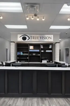 True Vision optical shop reception area with black cabinets and monitors on a counter
