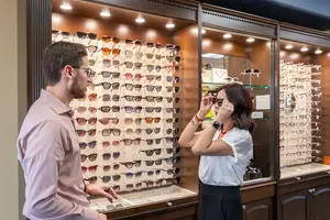 A man and a woman are inside a store looking at glasses on display