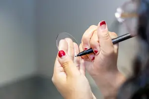 A person is holding a lens in their hand and drawing on it with a pen.