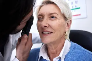 A doctor examining an elderly woman's eyes with a device