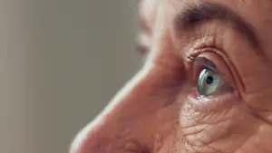 Close-up of an elderly person's face with wrinkles and a grayish-blue eye