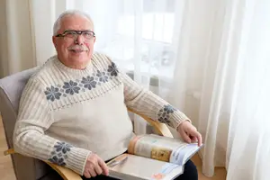 A man sitting on a chair while reading a book