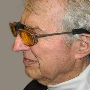 A close up of an older man wearing glasses with a serious expression