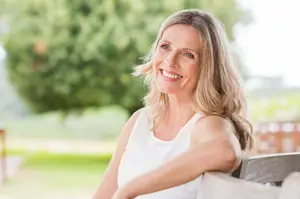 Woman sitting on a bench with a smile on her face in a park